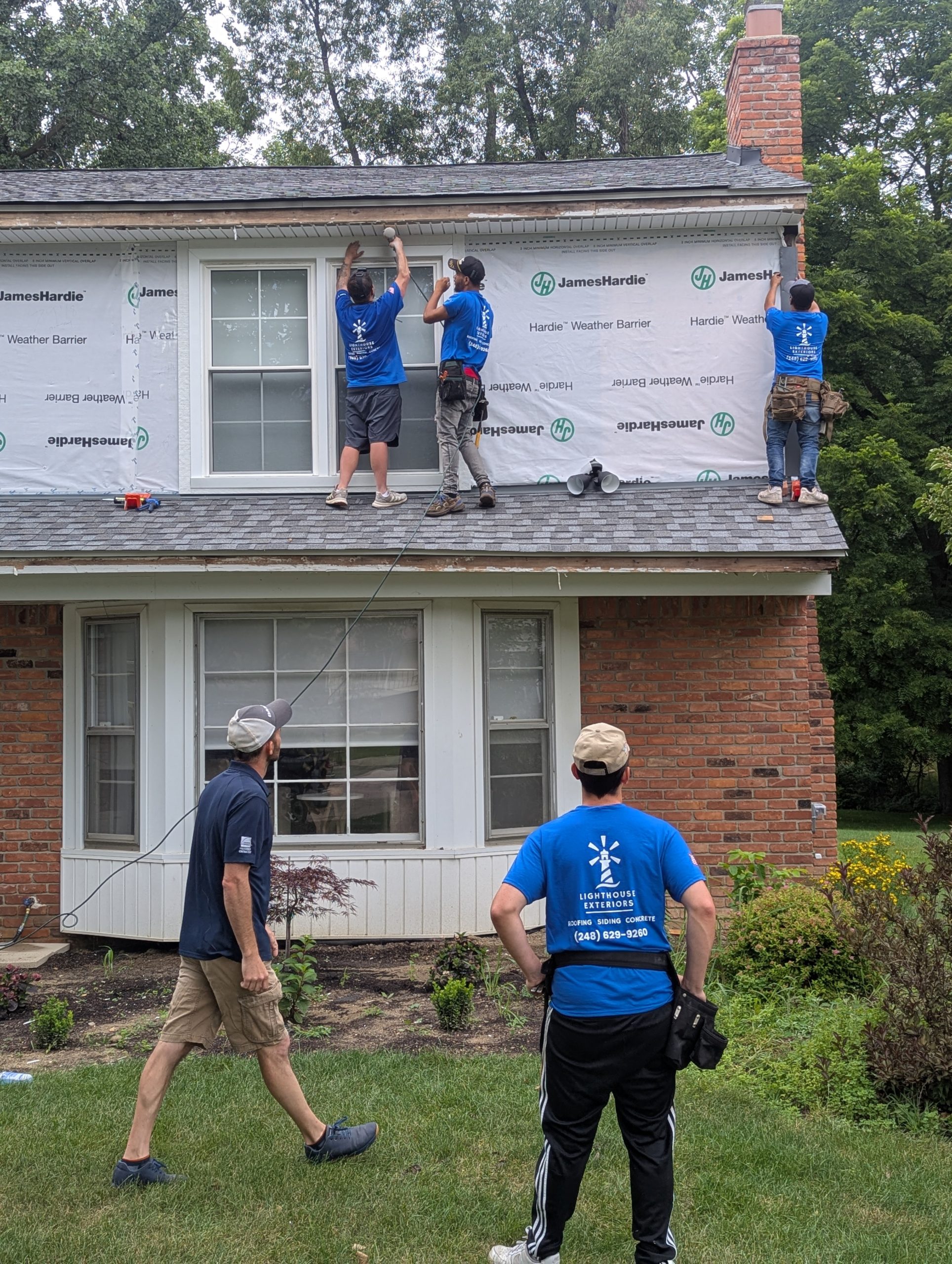 The Lighthouse Exteriors team working on a siding project